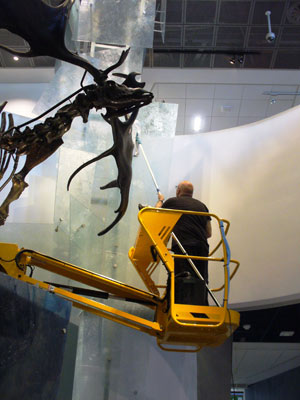 man in a small crane cleaning a high area of the museum display