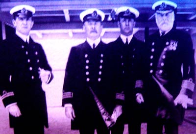 black and white photo of four men in naval uniform on the deck of a ship