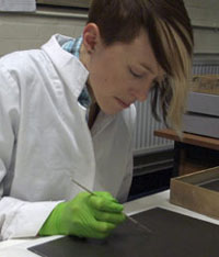woman wearing lab coat and gloves working on a large negative