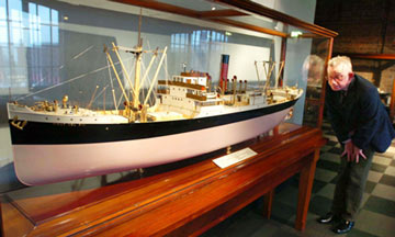 man looking at a ship model on display in the museum