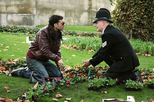 two men at a flower bed, one in police uniform