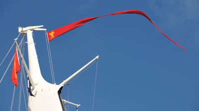 photo of a long thin red flag flying from the top of a liner
