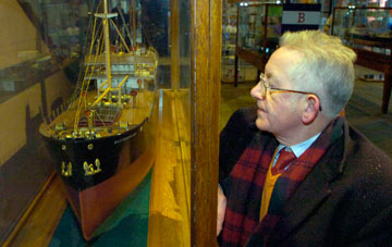 Stephen next to a model ship in a display case