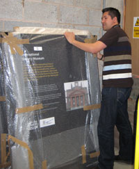 Richard Benjamin covering a museum display panel in bubble wrap
