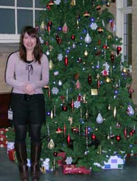 photo of a woman standing next to a Christmas tree