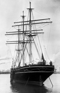 Black and white photo of a masted ship on a calm sea