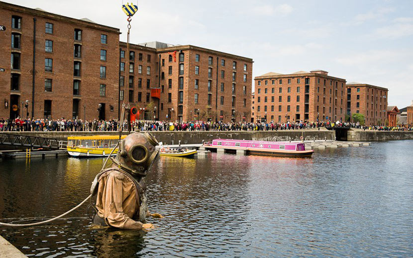 Enormous wooden puppet of a diver, standing in the water by the Albert Dock