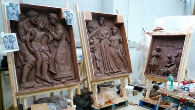 Three clay panels sculpted into scenes with figures in classical clothing
