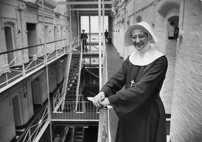 a nun standing by the balcony in a prison