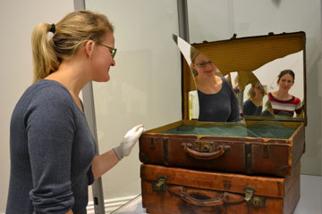Woman looking into a suitcase containing shards of glass