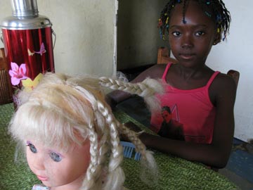 A little girl plays with her doll's hair