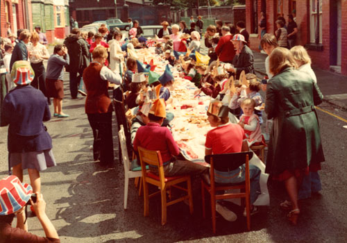 people around a long party table in the street