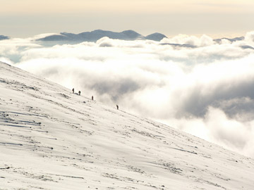 A small group of men on a very big white slope of a mountain