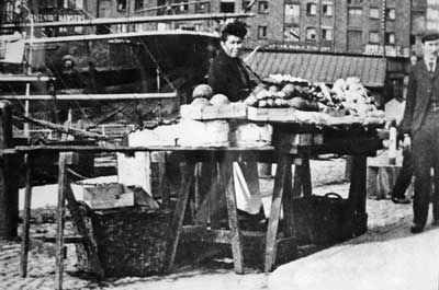 Black and white photo of a Black woman at a market stall in a town