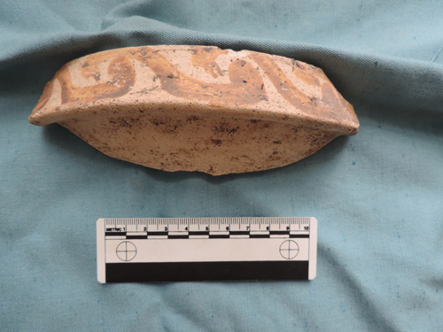 This fragment of mortarium is decorated with a repeating pattern using a red slip, a liquid clay applied just before the pot is fired. 