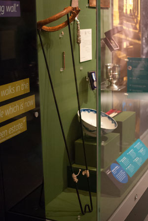 Splint with long sticks and padded ends for attaching to a leg, in museum display case