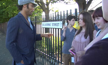 people talking by park railings and a 'Selborne Street' sign