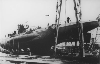 Black and white photo of a submarine being hoisted out of water.