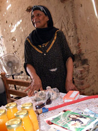 woman in traditional Egyptian clothing at a table with two small fluffy birds