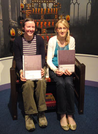two young women with certificates sitting in a fancy chair