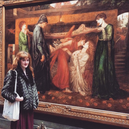 A Pre-Raphaelite looking visitor stands next to a Pre-Raphaelite painting in the Walker Art Gallery