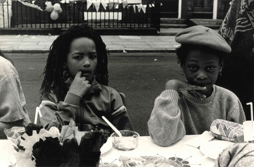 two children sitting at a table at a street party