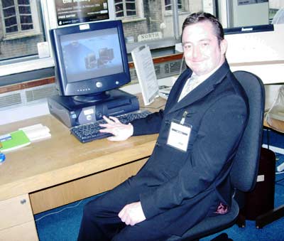 photo of a smiling man in a suit sitting at a computer terminal