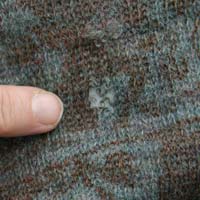 Close up of a hole in the woollen dress