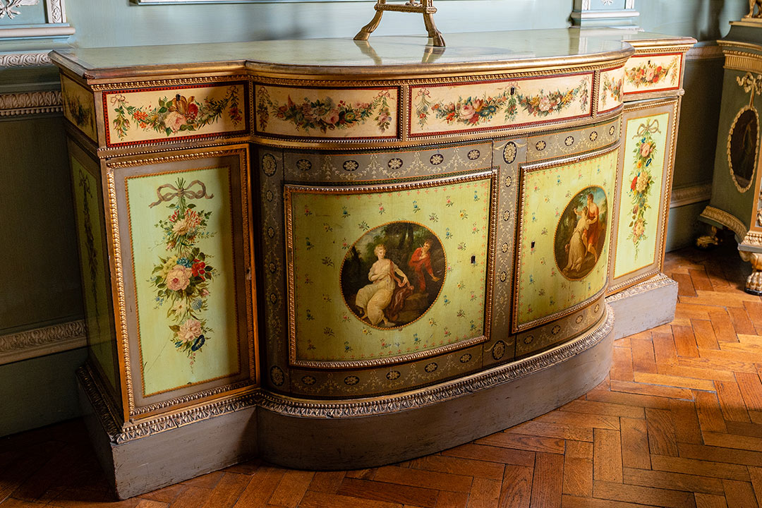 scenes of lovers in decorative enamel panels on low cupboard