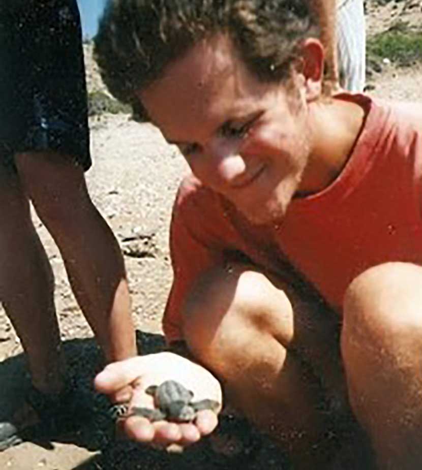 John holding a baby turtle on the beach