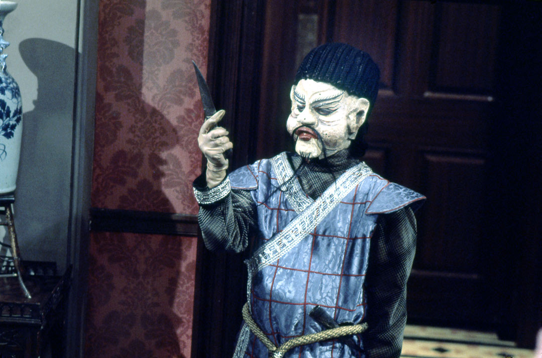 Mr Sin, a Doctor Who alien wearing traditional Chinese clothing, holding a knife