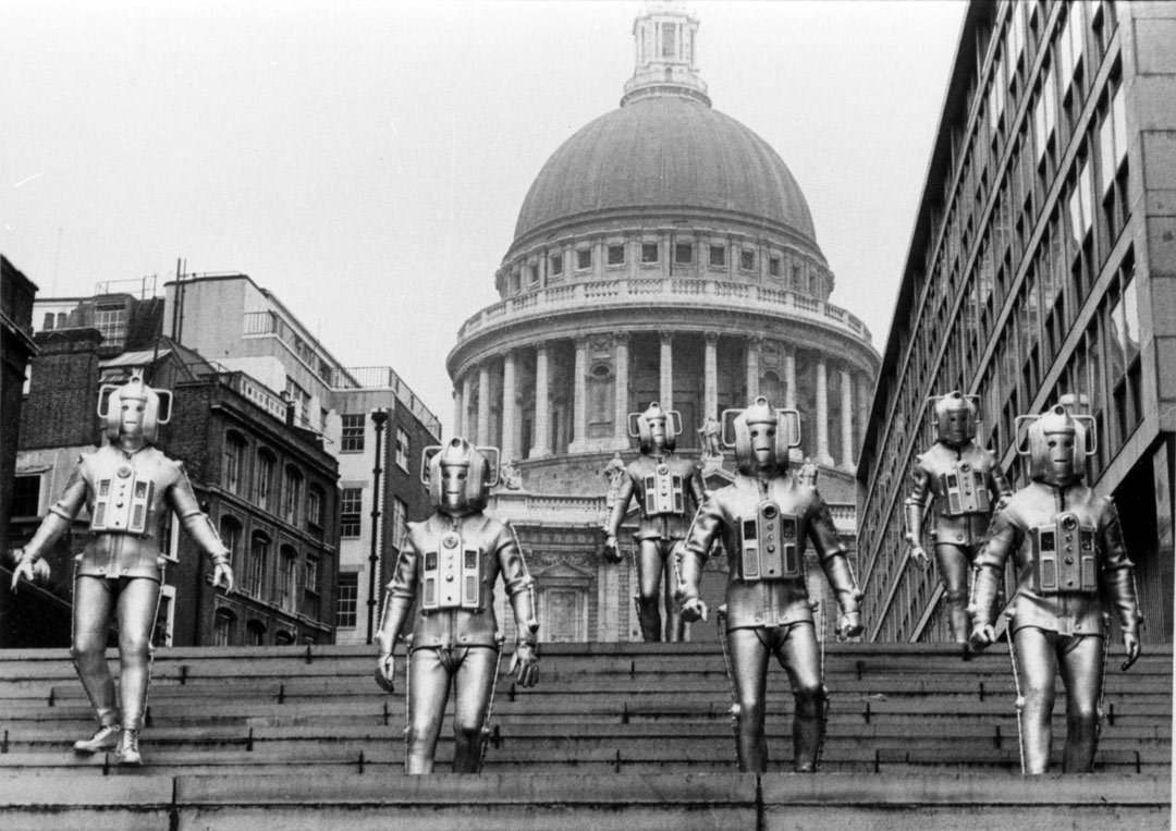 Six Cybermen silver robots in London, with St Pail's cathedral behind them