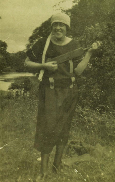 Smiling woman pretending to play a cricket bat like a guitar
