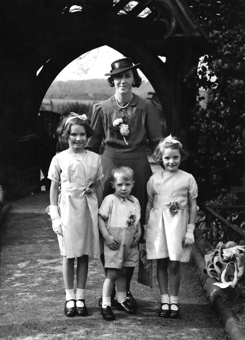 smartly dressed mother and three children by an arched gateway