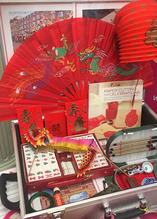 open suitcase containing Chinese memorabilia including fans, lanterns, photos and more