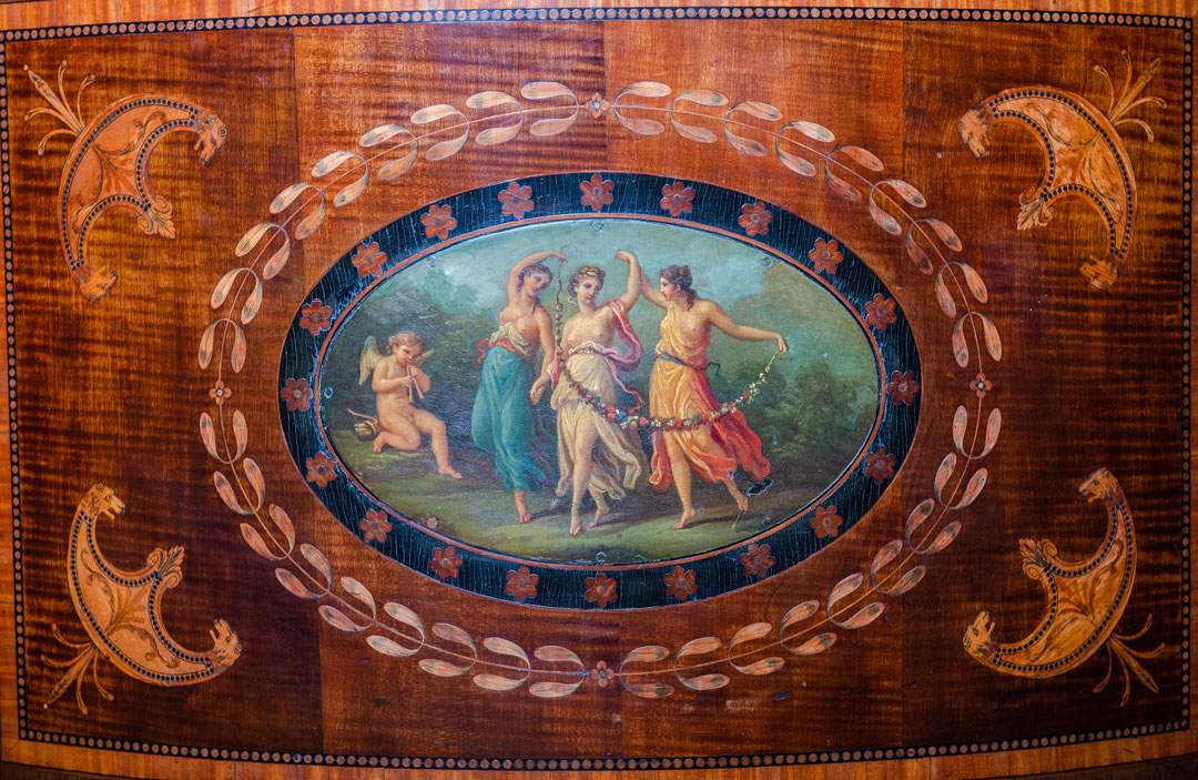 painting of three women dancing by Cupid, in a decorative wooden panel
