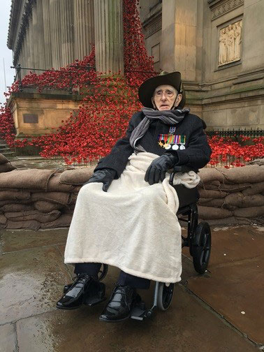 Philip wearing his medals, sat in a wheelchair in front of poppy sculpture