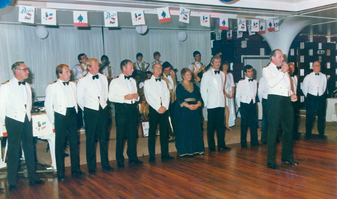 Lynn Littler in evening dress standing with a long line of men in uniform at a social event