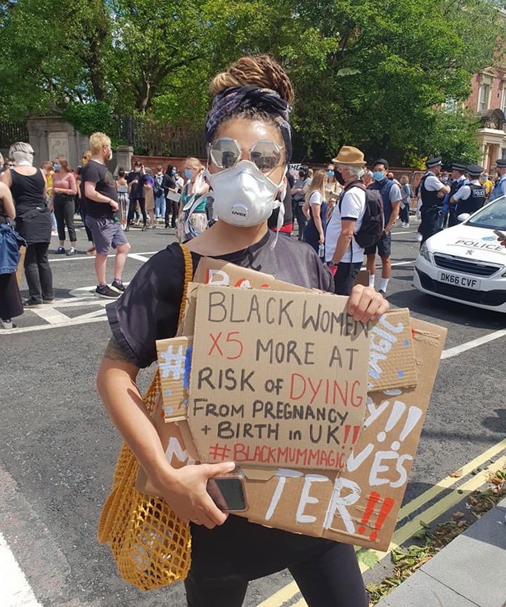 Tisian holding a cardboard BLM protest sign in Liverpool