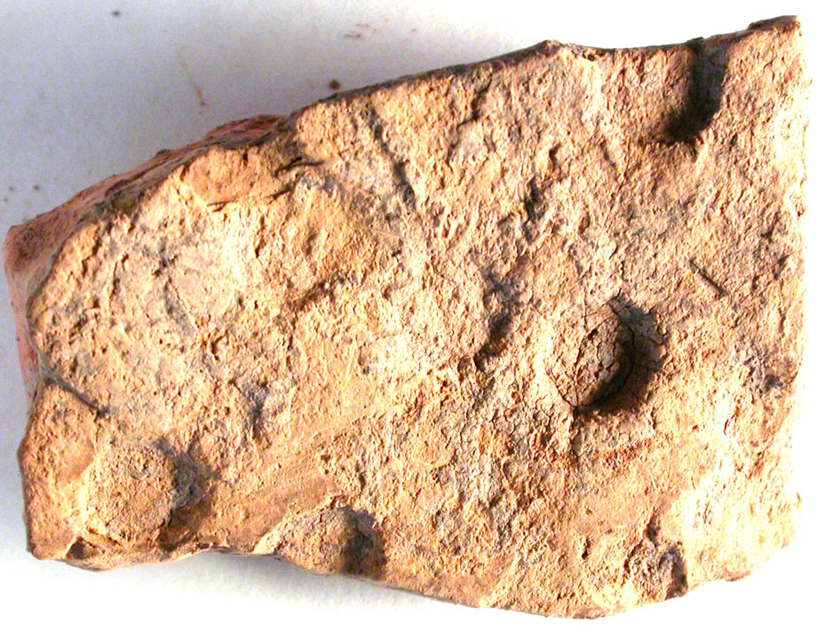 old tile with round indentations made by a hobnailed boot