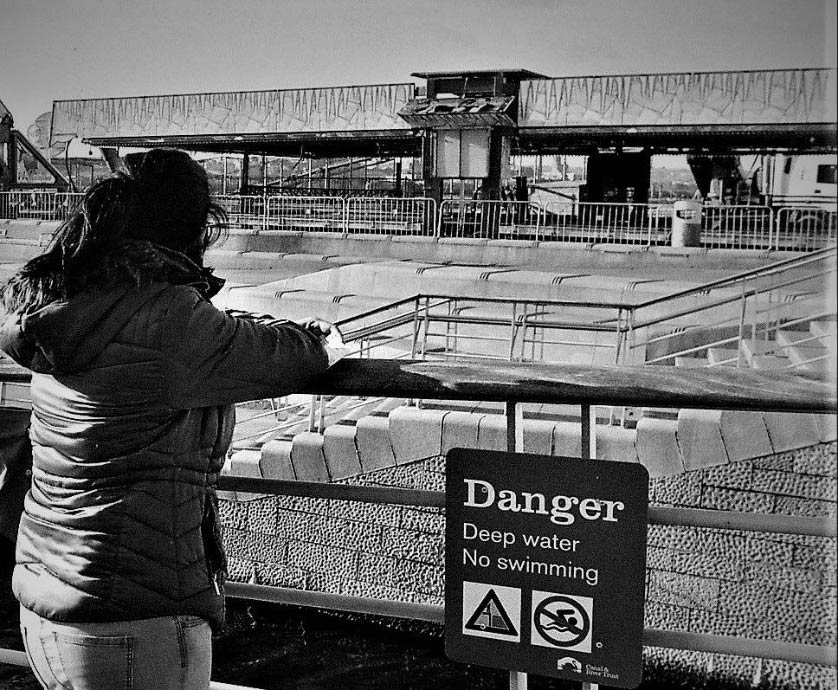 woman standing by a danger sign by docks