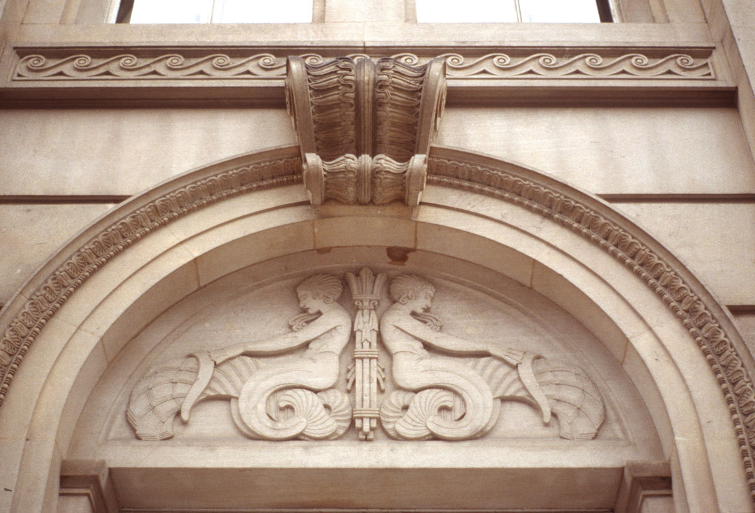 mermaid figures carved in stone in archway above door