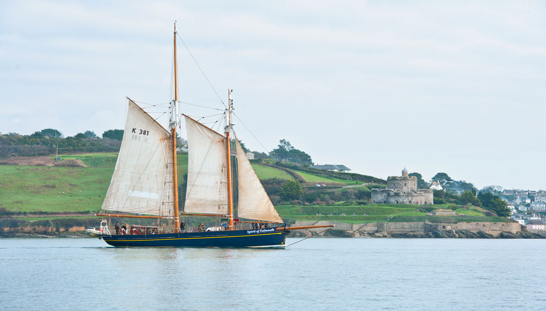 sailing ship with a castle on the coast in the background
