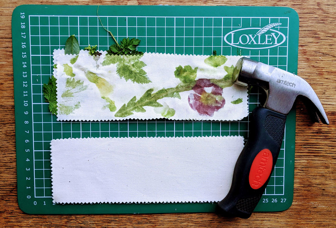 hammer next to flower and leaves on a fabric strip on a cutting board