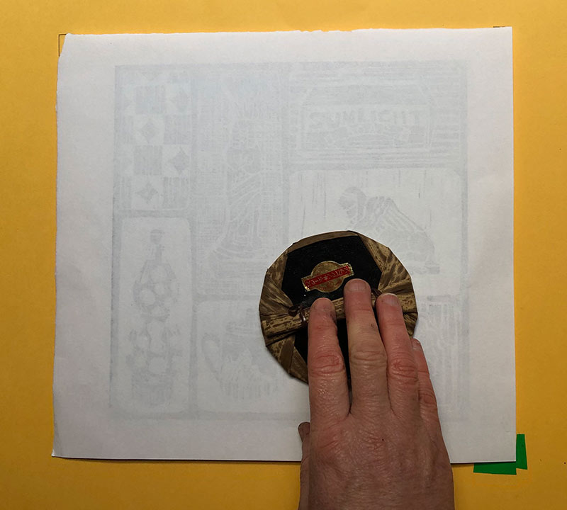 hands rubbing printing block onto paper